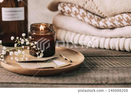 Cozy still life with candle, flowers, and books on dark table Cozy still life with candle, flowers, and books on dark table 140898208