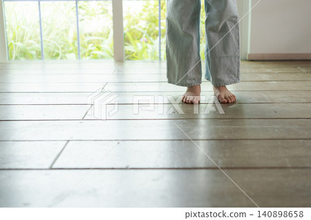 A girl walking barefoot on a wooden floor. 140898658