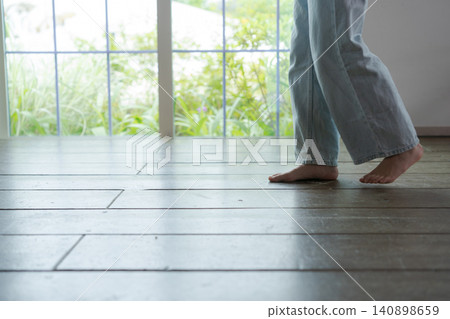 一個女孩赤腳走在木地板上。 140898659