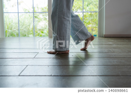 一個女孩赤腳走在木地板上。 一個女孩赤腳走在木地板上。 140898661