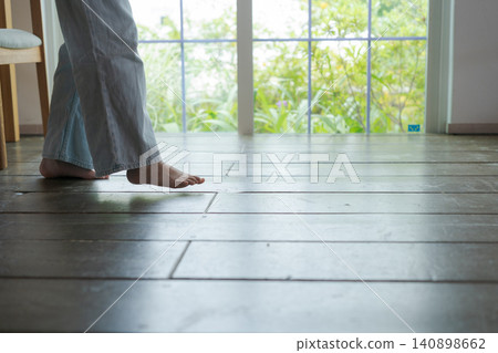 一個女孩赤腳走在木地板上。 一個女孩赤腳走在木地板上。 140898662
