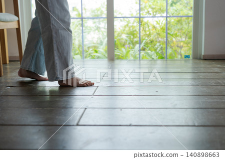 一個女孩赤腳走在木地板上。 一個女孩赤腳走在木地板上。 140898663