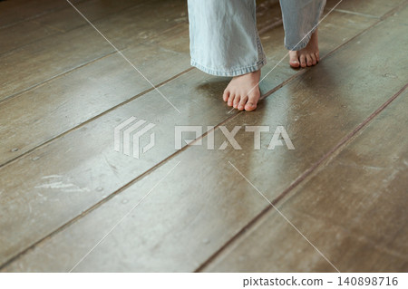 A girl walking barefoot on a wooden floor. A girl walking barefoot on a wooden floor. 140898716