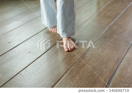 一個女孩赤腳走在木地板上。 一個女孩赤腳走在木地板上。 140898719
