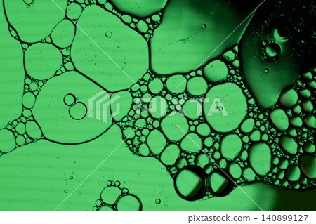 Close view of green fluid bubbles clustered in organic shapes, creating abstract cellular pattern with dark edges 140899127