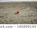 A single red bucket left on the beach 140899149