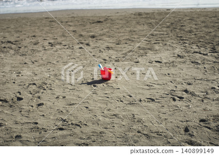 A single red bucket left on the beach A single red bucket left on the beach 140899149