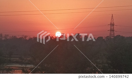 Silhouetted power lines against an orange sunset sky Silhouetted power lines against an orange sunset sky 140899742