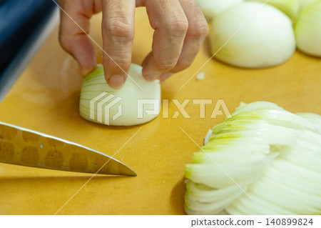 Stock photo of a man slicing an onion. Stock photo of a man slicing an onion. 140899824