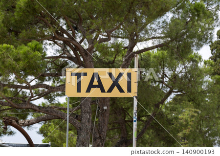 The sign "Taxi" against a green tree 140900193