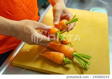 A man's hands preparing freshly picked carrots. A man's hands preparing freshly picked carrots. 140900243