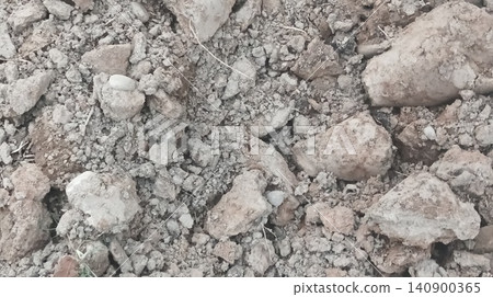 Close-up overhead shot of rough tilled soil texture with a small patch of green grass Close-up overhead shot of rough tilled soil texture with a small patch of green grass 140900365