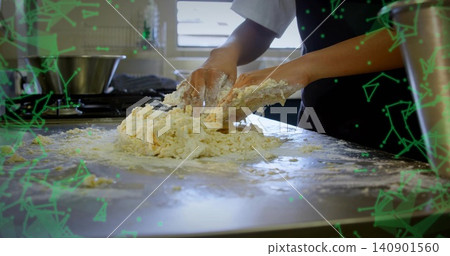 Kneading chef wearing white top and dark apron, pressing sticky dough on steel counter with flour 140901560