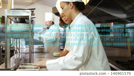 Leaning female chef wearing white jacket headband arranging pans at kitchen pass, binary overlay Leaning female chef wearing white jacket headband arranging pans at kitchen pass, binary overlay 140901570