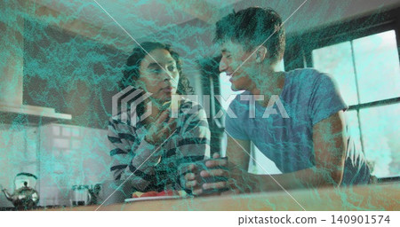Talking adults in light blue tee, striped top leaning on kitchen counter, holding mug near plate Talking adults in light blue tee, striped top leaning on kitchen counter, holding mug near plate 140901574