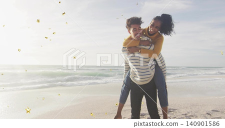 Carrying man carrying woman piggyback on beach shore in sweaters and jeans golden stars, copy space Carrying man carrying woman piggyback on beach shore in sweaters and jeans golden stars, copy space 140901586
