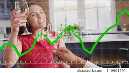 Toasting woman in red dress raising wine glasses at modern kitchen with green stock graph overlay Toasting woman in red dress raising wine glasses at modern kitchen with green stock graph overlay 140901591