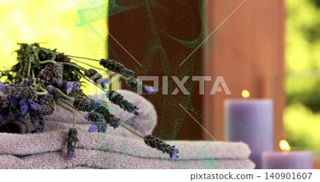 Resting dried lavender bundle on terry towels at spa table near wooden panel, lit purple candles 140901607