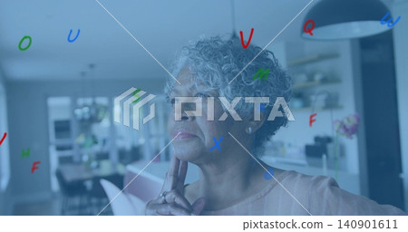 Thinking senior woman touching chin, wearing striped top in kitchen, colorful letters overlaying Thinking senior woman touching chin, wearing striped top in kitchen, colorful letters overlaying 140901611