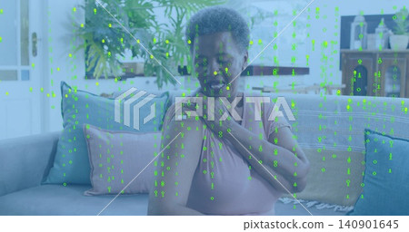 Sitting senior woman touching shoulder with hand on sofa in short-sleeve pink top, green overlay Sitting senior woman touching shoulder with hand on sofa in short-sleeve pink top, green overlay 140901645