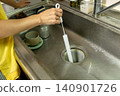 A woman's hands as she cleans the kitchen drain. 140901726