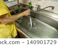 A woman's hands as she cleans the kitchen drain. 140901729