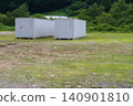 Two containers lined up in a grassy field 140901810