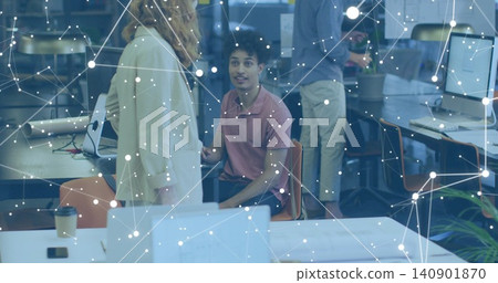 Looking man in pink polo talking to standing woman in light coat at workspace, with monitors Looking man in pink polo talking to standing woman in light coat at workspace, with monitors 140901870
