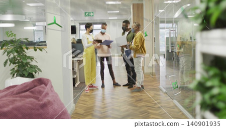 Reviewing four masked coworkers holding tablet and folders in open-plan office, casual attire Reviewing four masked coworkers holding tablet and folders in open-plan office, casual attire 140901935