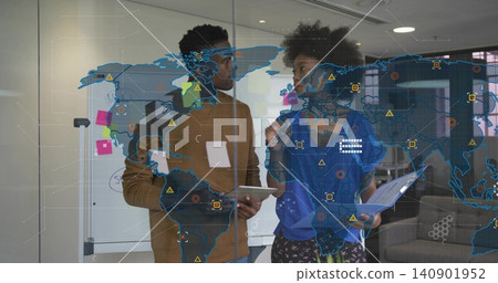 Discussing team wearing brown knit and blue top holding tablet and folder in office, map overlay 140901952