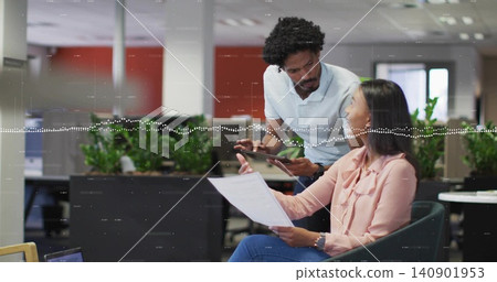 Discussing woman in pink blouse, man in white polo leaning over tablet and document in office 140901953