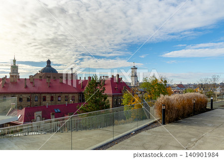 A panoramic view of an old European city featuring terracotta rooftops, architectural landmarks, and lush greenery under a cloudy sky A panoramic view of an old European city featuring terracotta rooftops, architectural landmarks, and lush greenery under a cloudy sky 140901984