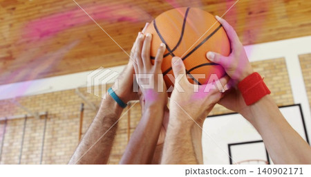 Reaching cluster of four arms grasping orange basketball at gym court with teal and red wristbands Reaching cluster of four arms grasping orange basketball at gym court with teal and red wristbands 140902171