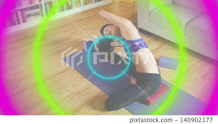 Bending Korean woman at-home on mat using blue block and red cushion, wearing sportsbra, neon rings Bending Korean woman at-home on mat using blue block and red cushion, wearing sportsbra, neon rings 140902177