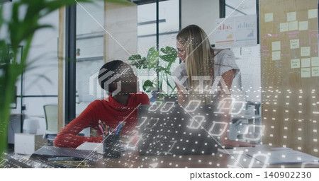 Collaborating two women in red sweater and light blouse discussing project at office, with laptop 140902230