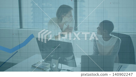 Talking, two women in workwear leaning and sitting at office desk with laptop monitor blue overlay Talking, two women in workwear leaning and sitting at office desk with laptop monitor blue overlay 140902247