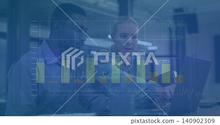 Discussing two colleagues wearing yellow vest and shirt over laptop in modern office, chart overlay 140902309