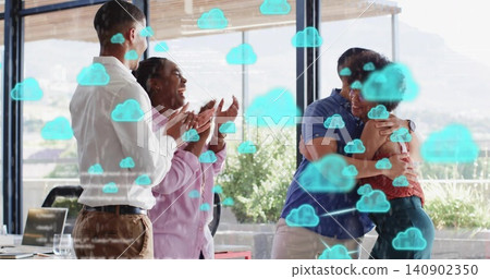 Clapping coworkers in business attire hugging and celebrating in glass office with laptop and cloud Clapping coworkers in business attire hugging and celebrating in glass office with laptop and cloud 140902350