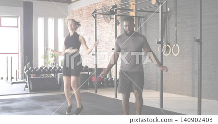 Skipping partners wearing black crop top and gray t-shirt in fitness studio, with jump ropes Skipping partners wearing black crop top and gray t-shirt in fitness studio, with jump ropes 140902403