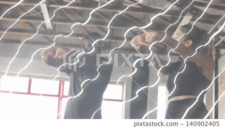 Holding bent elbows fitness partners raising arms in industrial gym with red windows wearing gear Holding bent elbows fitness partners raising arms in industrial gym with red windows wearing gear 140902405