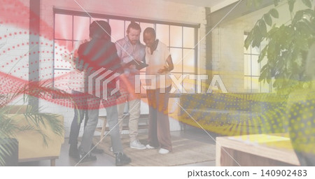 Viewing tablet, four colleagues leaning in at loft workspace in smart casual outfits, with plants 140902483