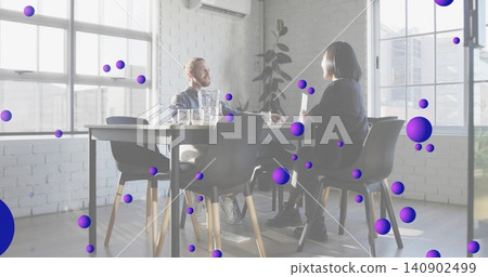 Talking bearded man and Asian woman in biz-casual checking laptop on office table, purple spheres Talking bearded man and Asian woman in biz-casual checking laptop on office table, purple spheres 140902499
