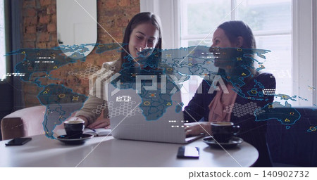 Working two women wearing blazers leaning over laptop at cafe, with coffee cups phone map overlay Working two women wearing blazers leaning over laptop at cafe, with coffee cups phone map overlay 140902732
