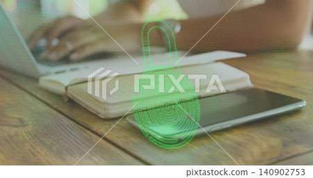 Showing smartphone and notebook with green padlock fingerprint on wooden table, hands typing Showing smartphone and notebook with green padlock fingerprint on wooden table, hands typing 140902753