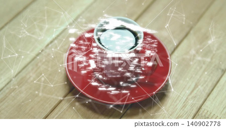 Showing red ceramic cup plus saucer holding dark liquid on light wood surface with digital overlay Showing red ceramic cup plus saucer holding dark liquid on light wood surface with digital overlay 140902778