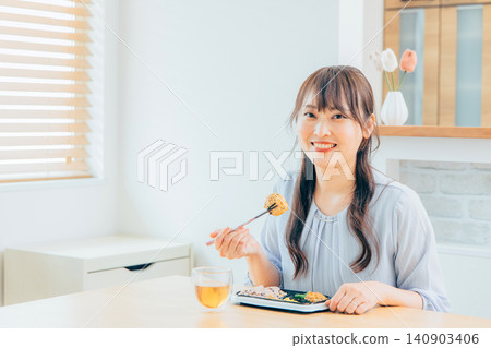一位微笑的日本女性在家中享用美食：一種自然的生活方式 140903406