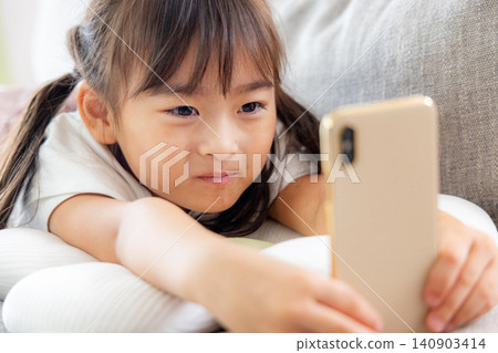 A girl using her smartphone on the sofa A girl using her smartphone on the sofa 140903414