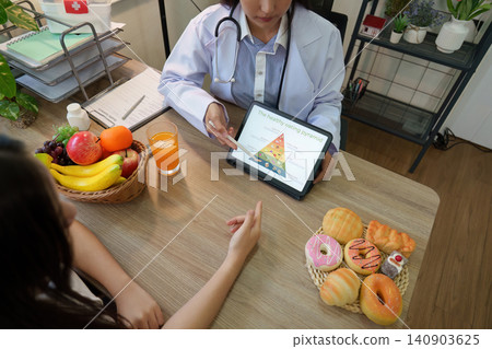 Nutritionist showing healthy eating pyramid on tablet to patient during consultation Nutritionist showing healthy eating pyramid on tablet to patient during consultation 140903625