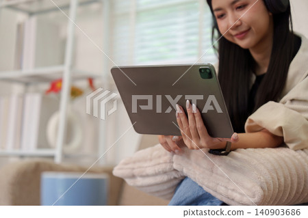 Asian woman using digital tablet at home for entertainment and online browsing Asian woman using digital tablet at home for entertainment and online browsing 140903686