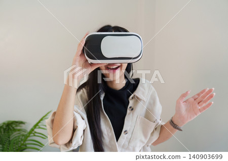 Asian woman wearing VR headset for immersive virtual reality experience Asian woman wearing VR headset for immersive virtual reality experience 140903699